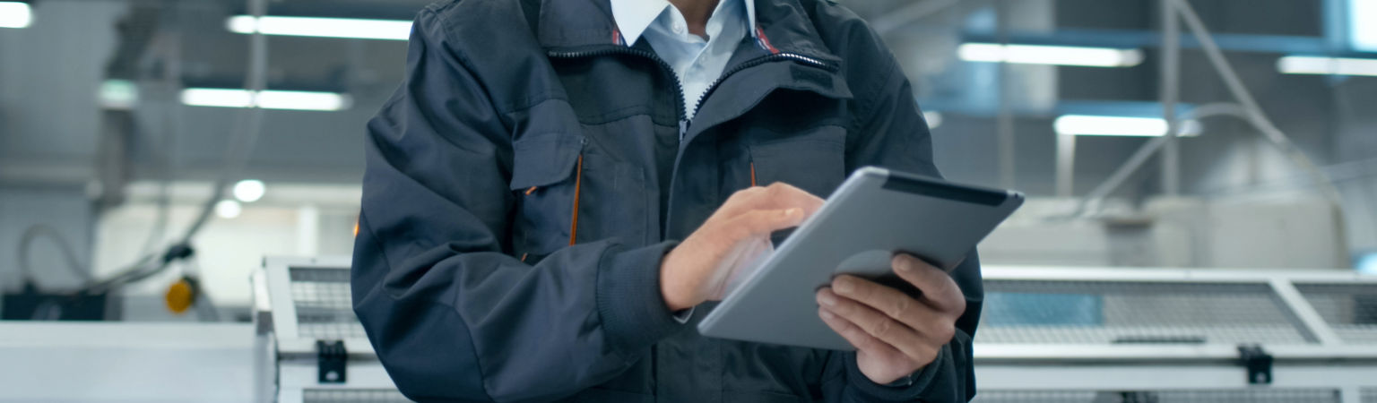 Operator w hali produkcyjnej monitoruje pracę zakładu na tablecie z systemem HDF MES